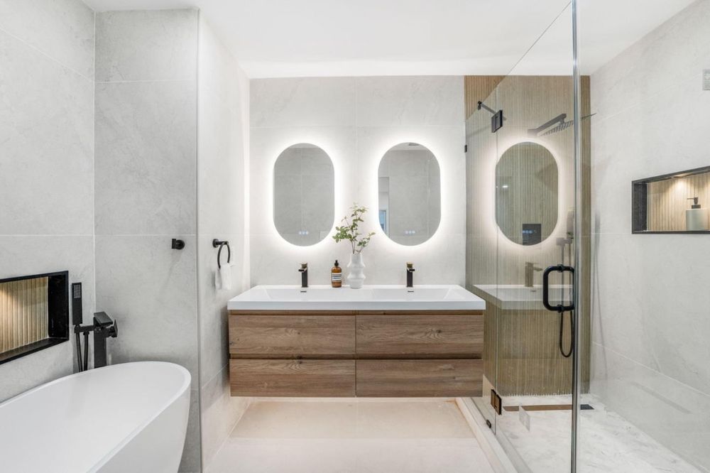 Primary bath with soaking tub and lit mirrors